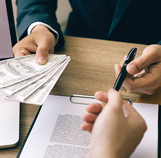 A man holding money while another person signs a contract at a store for a payday loan.