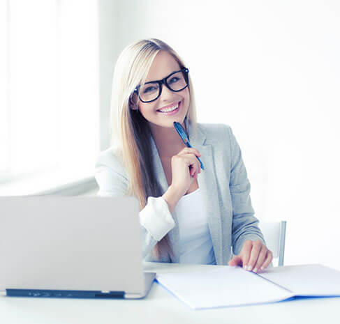 A woman in glasses sitting at a desk with a laptop, working at USA Cash Services.