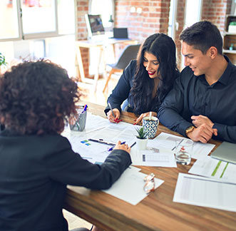 Three business people discussing Western USA Payday Loan Extensions at a table, surrounded by papers.