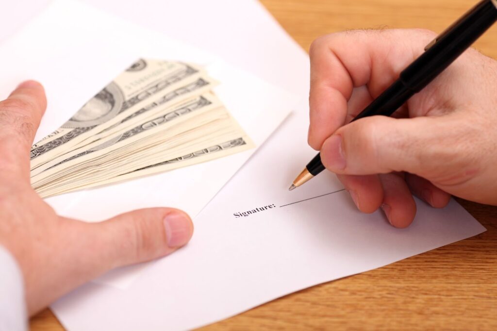 A person filling out a loan application for a car with the words title loans, car title loans, vehicle title loans in the background.