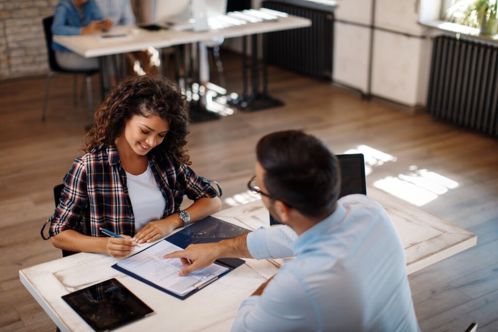 A man and woman sitting at a table with a laptop, discussing installment loan options and traditional bank loans.