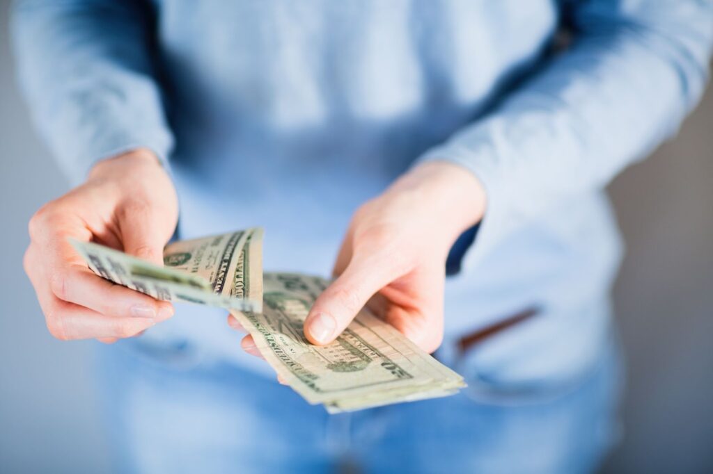 A person holds a stack of cash, symbolizing quick access to online payday loans for those with bad credit.