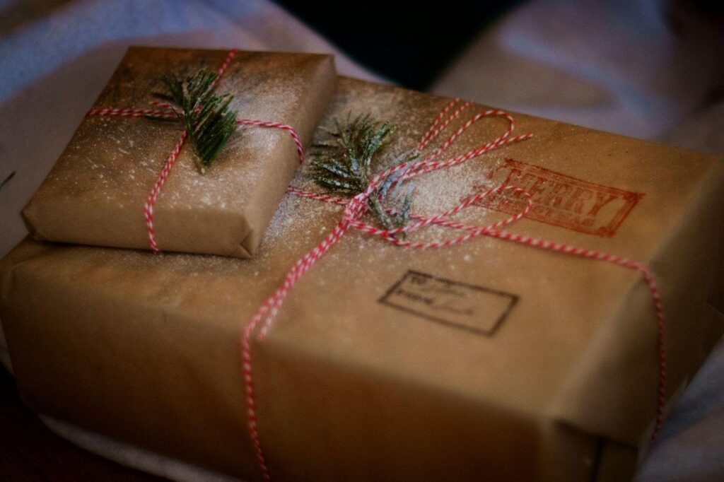 Two beautifully wrapped gifts adorned with pine needles for a festive holiday look