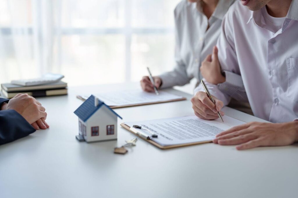 A man and woman collaborate at a table, both engaged in signing important paperwork