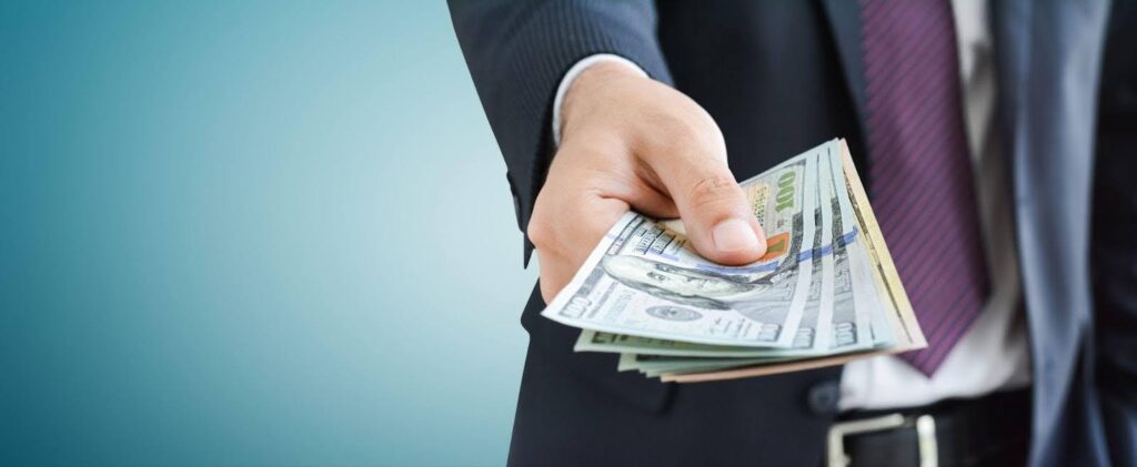 A well-dressed man in a suit displays a bundle of money, representing financial prosperity