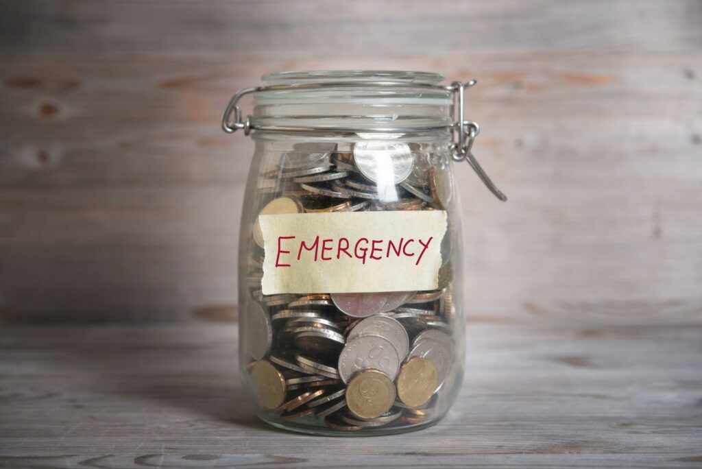 A clear jar filled with coins, symbolizing emergency savings for financial emergencies and avoiding payday loans.