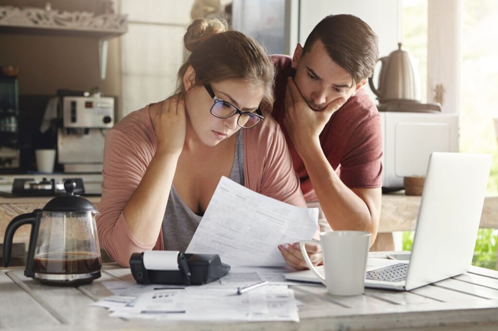 Two individuals review a document on a table, discussing payday loans for financial emergencies and managing their finances.