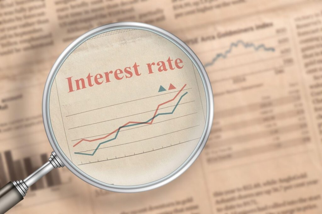A magnifying glass highlights a newspaper section with a graph labeled Interest rate