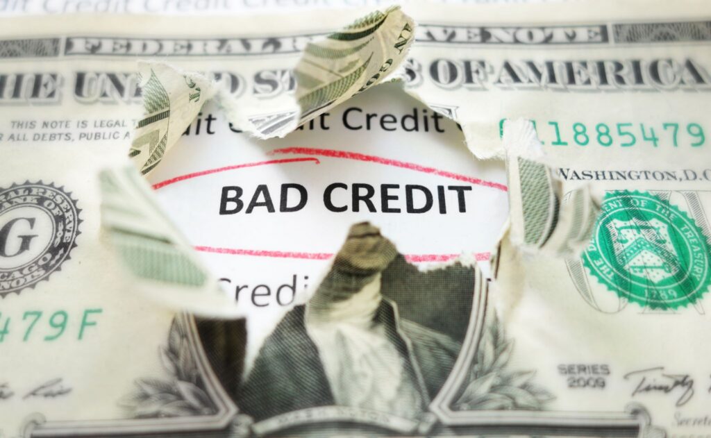 A torn US dollar bill revealing the words BAD CREDIT circled in red underneath.